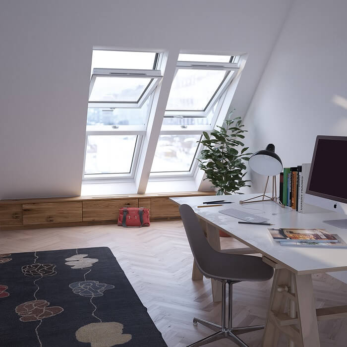 A modern desk in a well-lit attic conversion with a colourful rug underneath